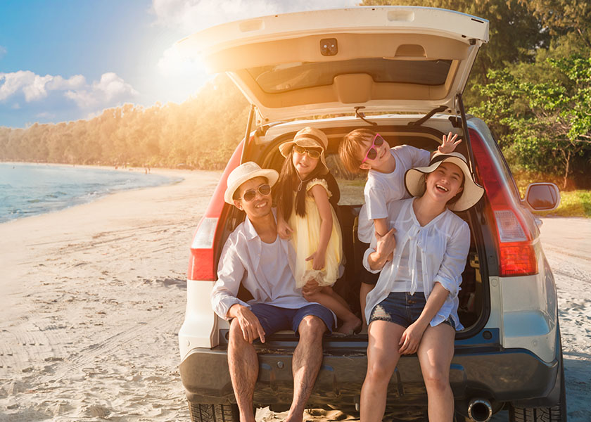 Smiling family in minivan on beach