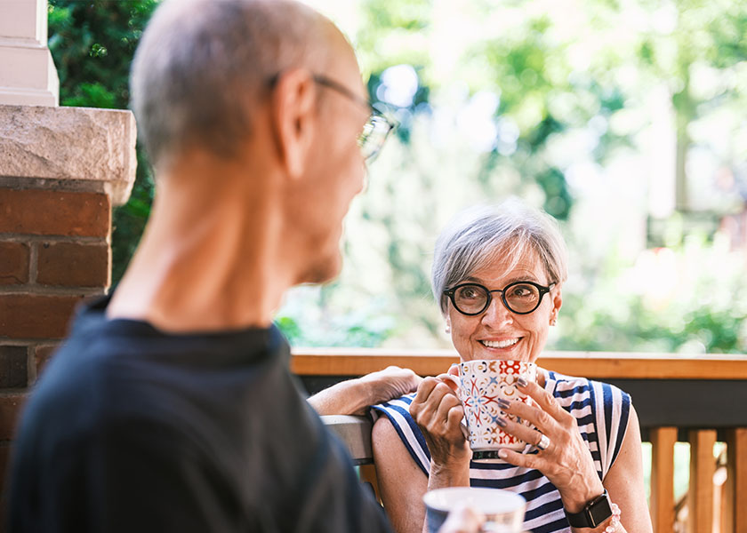 A mature couple sits on their front porch enjoying their coffee—and their retirement.