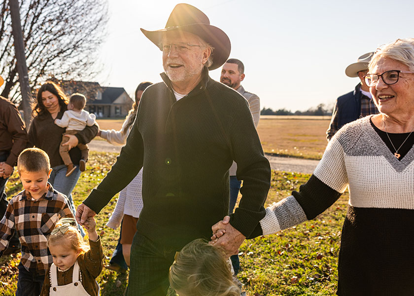 A large, multigenerational family walks through an expansive yard, many holding hands. Leaving a legacy.